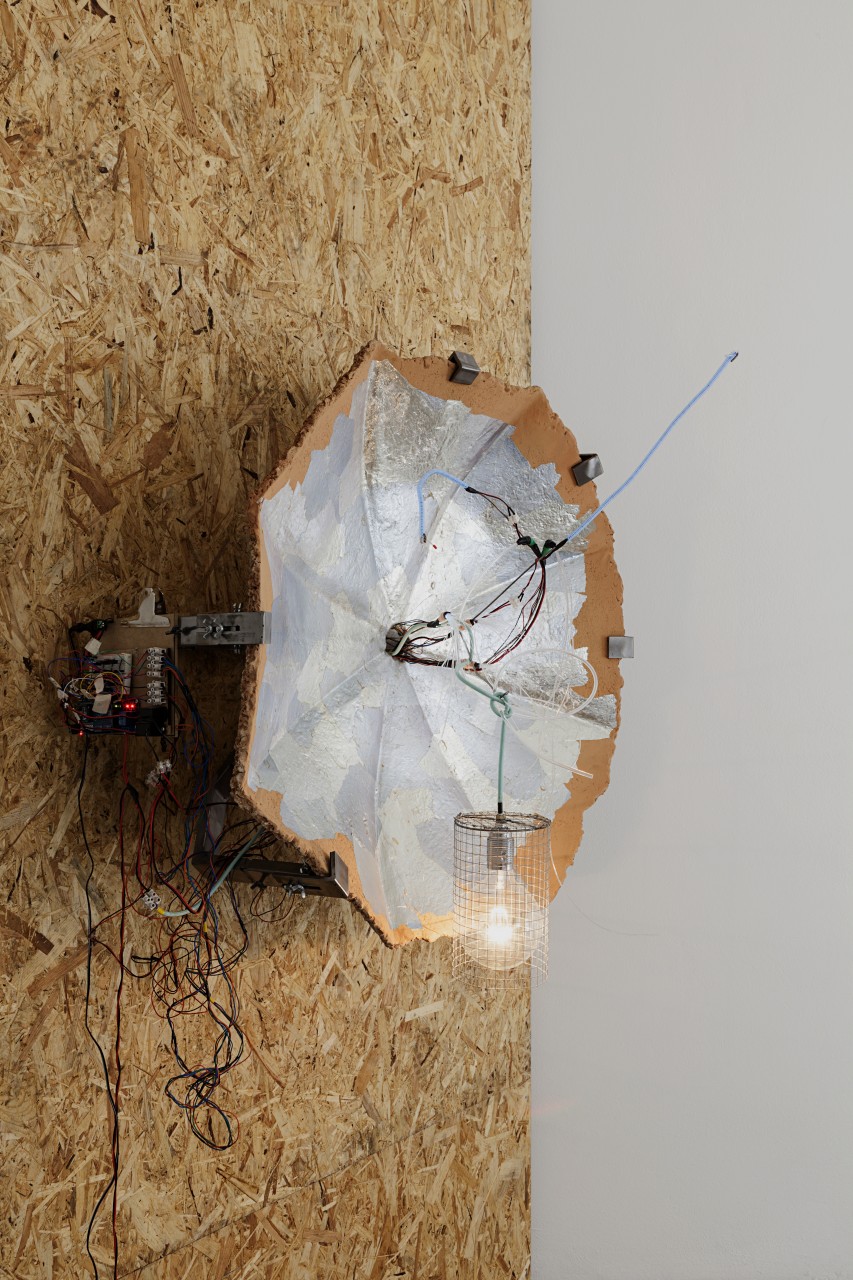 Amy Lien & Enzo Camacho, <i>Untitled (CyberCeramic Prototype 1 Mathew at MiArt, Gluck50)</i>, 2015, two-part input-output sculpture. Part one: hand molded refratteria terra cotta umbrella cast, joss paper collage, embedded steel pole, Fabbrica Ceramiche Giuseppe Mazzotti 1903 re-edition of 1930 Nicolaj Diulgheroff Futurist Teapot design (ceramic, glaze), wire basket, sensors for temperature, light, motion, and audio, Arduino and X-Bee wireless transmitter, steel wall mount. Part two: hand molded refratteria terra cotta umbrella cast, joss paper collage, steel wires, electroluminescent wires, LED lights with fiber optic attachments, incandescent light bulb, wire light bulb cage, Arduino and X-Bee wireless receiver, code for expressing sensory input, steel wall mount, dimensions variable. Courtesy of Gluck50. Ph. Andrea Rossetti